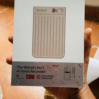 A hand holding the white packaging box for a Plaud Note AI voice recorder device, which is advertised as the world's number one AI voice recorder and winner of a Good Design Award 2024